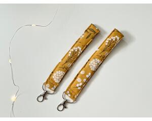 this floral keychain wristlet has mustard yellow background with dandelions all over the lanyard wristlet