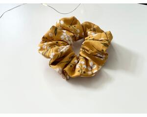 this mustard hair scrunchie has mustard yellow background with dandelions all over the ponytail