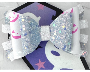 Soft lavender glitter faux leather, with loops of iridescent ribbon, tied in w/ white faux leather w/ pink and lavender pumpkin face print. 