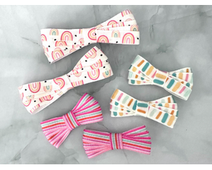 2" & 3 " size bows on 3/8" ribbon. 4 loops on each side. Top is rainbow print, to right is a colorful dash print, bottom is a stripe print. 