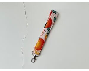 this orange keychain wristlet has a light pink background with tiny white polka dots with citrus orange all over the key strap