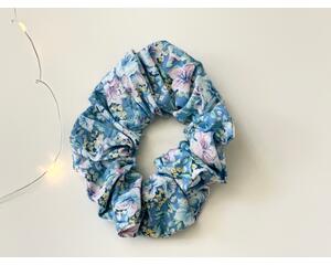 this blue floral scrunchie has a blue background with some blue flowers. The flowers are small in colors light pink and blue