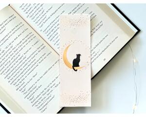 this pink moon bookmark has a light pink background with stars at the top, and bottom and around the crescent moon with a cat sitting on it.