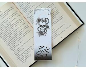 this skull bookmark has white marble background with spider web on of the book mark, a skull in the middle, and bats coming out of the dark