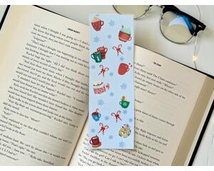 this hot chocolate bookmark has a blue background with hot cocoa, candy cane, and snowflakes all over the page saver
