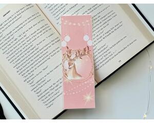 This pink Christmas bookmark has a pink background. There is a deer in the middle with Christmas lights hanging from the antlers. There is white Christmas ornaments hanging from the top with Christmas light on top of the bookmark.