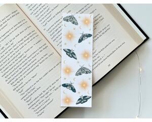 This moth bookmark has a white background with moths being beige and green. There are stars and moons all over the page saver