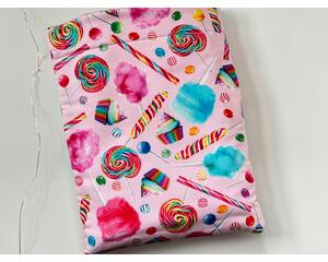 this candy book sleeve has a pink background with colorful cotton candy, lollipops, cupcakes all different candies