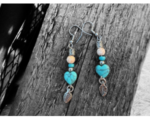 Handmade pair of western earrings are made of a turquoise-colored stone and other beads. At the end of the earring is a silver-plated leaf. 