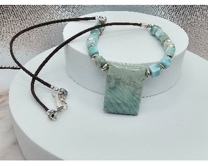 Light blueish green necklace with a rectangular pendant, cube beads on brown waxed cotton cord, with silver accents