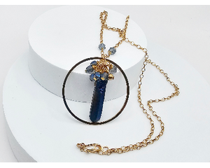 necklace features blue quartz pendant stone inside gold stainless steel circle with blue crystals wire wrapped on top hung on gold chain