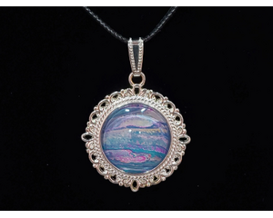 Beautifully painted glass pendant with blue, silver and pinks. The design is reminiscent of a seascape. Set in silver coated metal base.