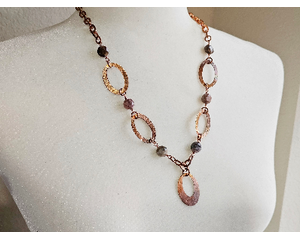 Handcrafted copper necklace with hammered washers, faceted petrified wood beads, and a 1" pendant, featuring a rustic boho design.