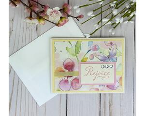 A pastel card with butterfly and floral scrapbook paper, light yellow cardstock, and a stamped sentiment with the words "rejoice" in pink.