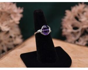 The image shows a silver ring with an amethyst double point gemstone wire wrapped with sterling silver wire. 