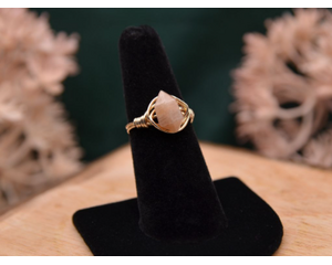 The image shows a gold ring with a peach moonstone double point gemstone wire wrapped with 14K gold-filled wire. 