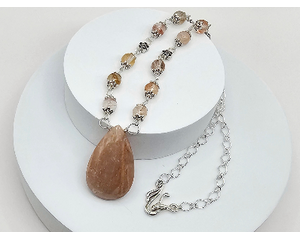 Handcrafted necklace with a peach moonstone pendant and sun hematoid beads on a stainless steel chain, 23" long with a 2" pendant.