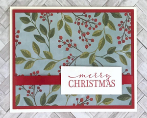 A Christmas card kit with winterberries paper, red cardstock mats, "Merry Christmas" stamped sentiments and red ribbons.