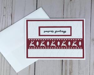 A Christmas card kit with embossed cardstock, red and green cardstock mats, reindeer die cuts and stamped "Seasons Greetings" sentiments.