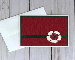 A floral Christmas card kit with embossed cardstock, green cardstock mats, handmade flower embellishments, green ribbons to make 6 cards.