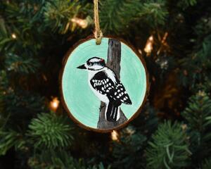 A hand-painted downy woodpecker wood slice ornament available at Cove Creek Photography.