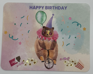 Watercolor circus bear on one wheeled bike surrounded by confetti, spilled popcorn, and candy 