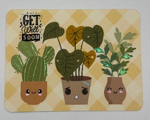 Get well card showcasing three plant friends, one adorned with bandage and brown leaves. Image on yellow and white plaid background.