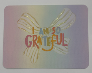 Watercolor backdrop featuring yellow striped bow with rainbow letters “I Am So Grateful”
