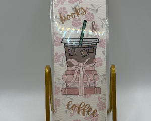 Laminated bookmark with stack of books with pink bow, iced coffee, on pink floral background 