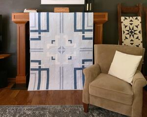 Modern quilt in shades of blue. 53 X 67. Solid fabrics on front; floral print on the back. Pattern is geometric inspired by a garden maze.