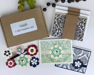 A handmade card making kit to make 6 cards with damask patterned paper, cardstock, die cut flowers, ribbons and cards and envelopes.