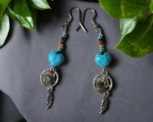 These dangle earrings are made of blue turquoise blue stones with other beads and tiny metal dream catchers