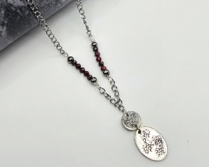 handcrafted necklace with textured pewter round and oval pendant, faceted garnet beads, and stainless steel chain