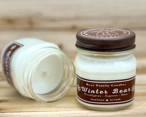 Pine and eucalyptus scented soy candle in 8oz mason jar. One jar standing up with lid on and one jar on its side with lid off.
