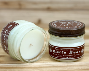 Cool mint and vanilla scented soy candle in 4oz mason jar. One jar standing up with lid on and one jar on its side with lid off.