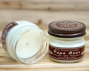 Apple, maple, and cinnamon scented soy candle in 4oz mason jar. One jar standing up with lid on and one jar on its side with lid off.