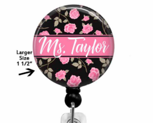 Pink flowers on a black background  with a name in the center.  The badge top is affixed to a retractable reel.  The top can be permanently attached to the reel or made to swap out designs.