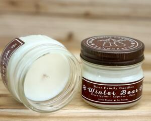 Pine and eucalyptus scented soy candle in 4oz mason jar. One jar standing up with lid on and one jar on its side with lid off.