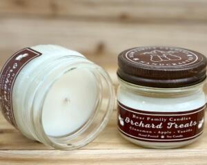 Apple cider scented soy candle in 4oz mason jar. One jar standing up with lid on and one jar on its side with lid off.