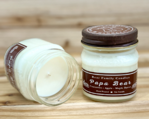 Maple, apple, and cinnamon scented soy candle in 8oz mason jar. One jar standing up with lid on and one jar on its side with lid off.