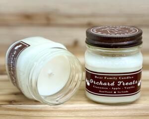 Apple cider scented candle in 8oz mason jar. One jar standing up with lid on and one jar on its side with lid off.