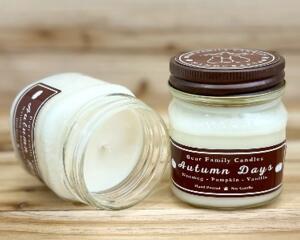 Pumpkin chai scented candle in an 8oz mason jar. One jar standing up with lid on and one jar on its side with lid off.