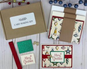 A handmade Christmas card kit with Christmas bulb paper, cardstock, embellishments, ribbons and envelopes to DIY 6 holiday greeting cards.