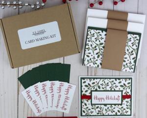 A handmade Happy Holiday card kit with holly scrapbook paper, cardstock, stamped sentiment, ribbon and envelope to DIY 6 Christmas cards.