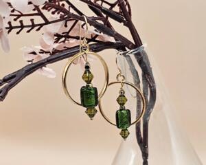 A pair of handmade 2-inch earrings with olive green vintage glass beads, green glass bicones and gold spacers with gold-plated circle frame
