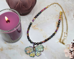 Colorful butterfly pendant necklace with black pearls and rainbow hematite beads on a gold chain.