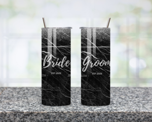 Black and silver glitter bride and groom tumblers with lids and straws shown together
