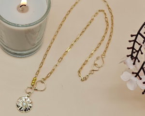 Gold-tone paperclip chain necklace with cubic zirconia sunburst pendant.