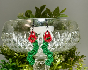 Pair of handmade free-standing lace earrings shaped like fuzzy green caterpillars with red flower-like faces and green eyes.
