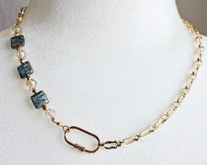 18 inch asymmetrical necklace, gold chain on one side, square blue Czech glass beads on other side, fastened with off-center carabiner clasp
